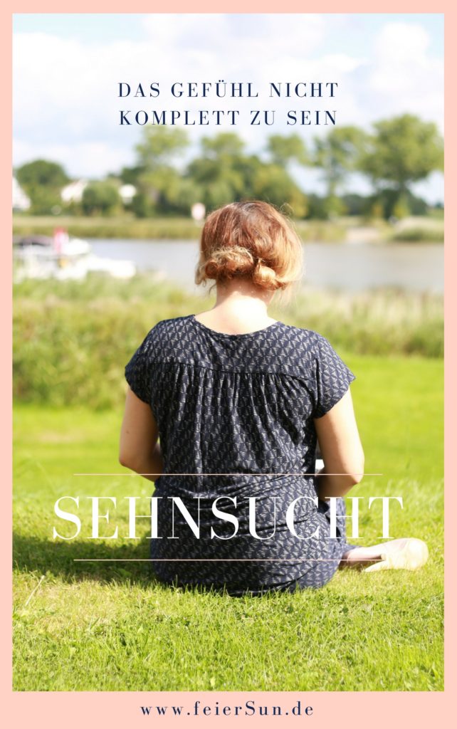 Eine Frau sitzt mit dem Rücken zur Kamera und schaut auf die Elbe. Sie trägt einen blauen Anzug und schaut in die Ferne mit der Aufschrift "das Gefühl nicht komplett zu sein - Sehnsucht - www.ferierSun.de!