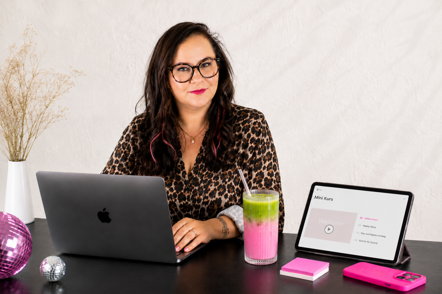 Jess Schonk sitzt am Laptop, daneben ein Tablet mit der Aufschrift Mini Kurs